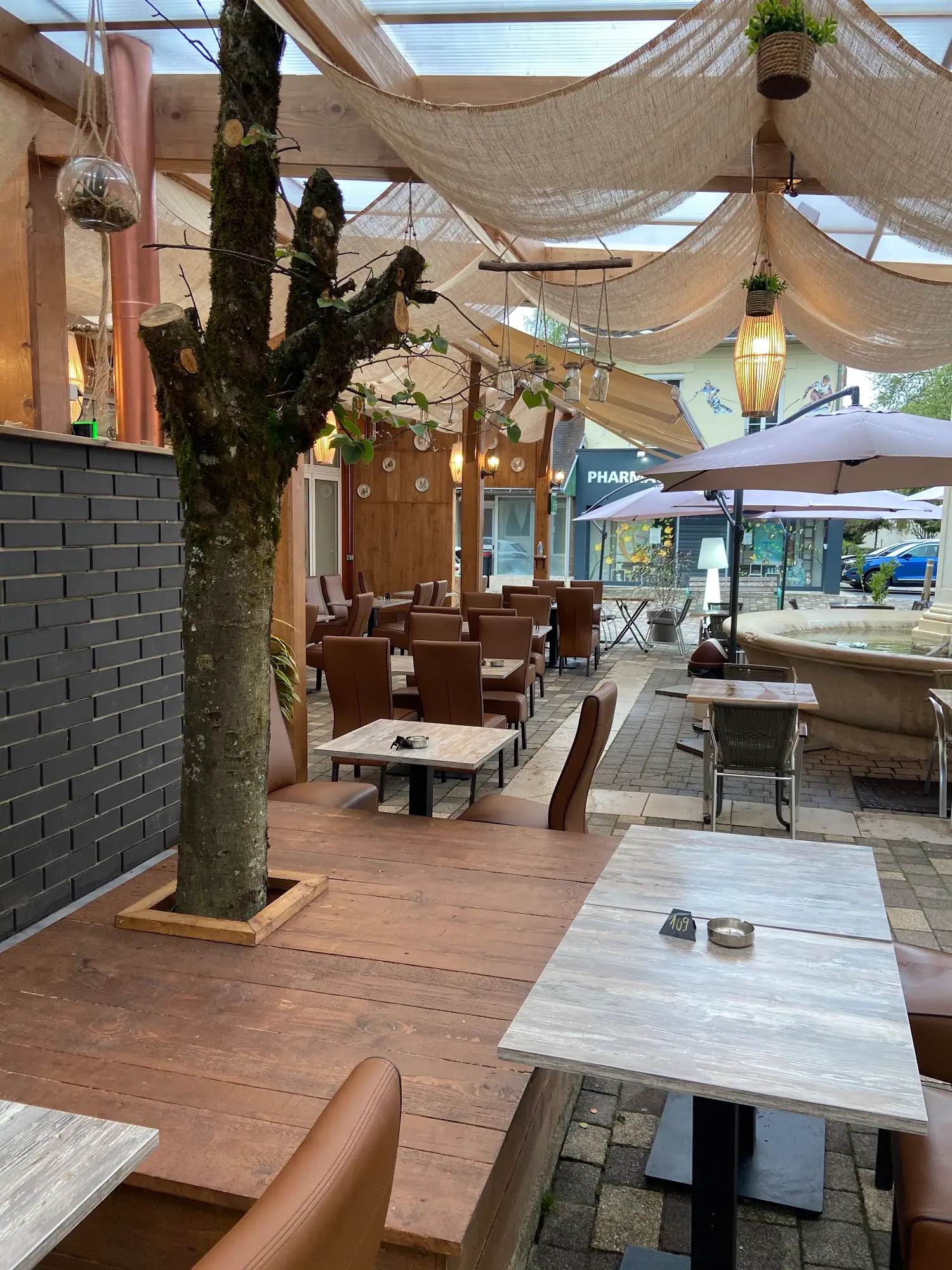 Terrasse couverte de voiles d'ombrage autour d'un arbre existant