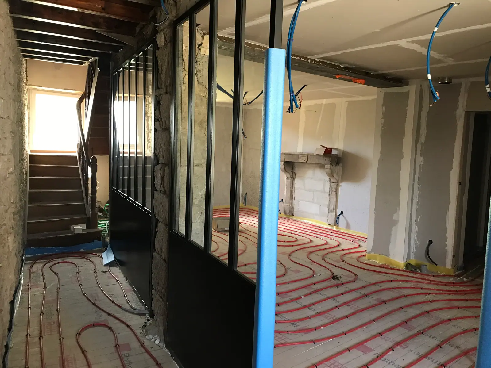 Chantier de rénovation : grandes menuiseries noires posées et plancher chauffant