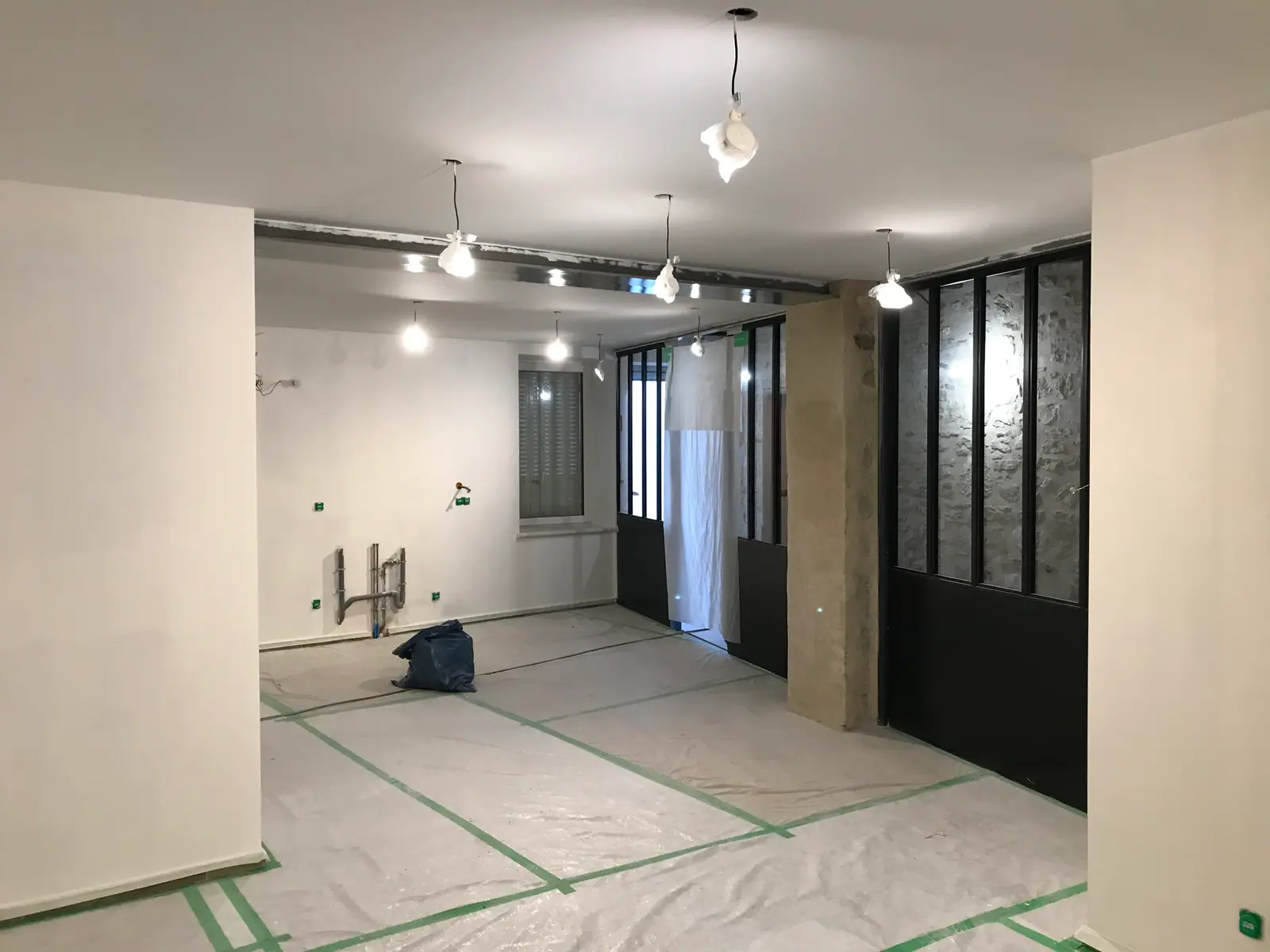Séjour en cours de finition, cloisons vitrées noires et sol clair